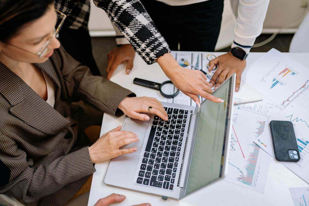 Woman and Colleagues Working around Laptop