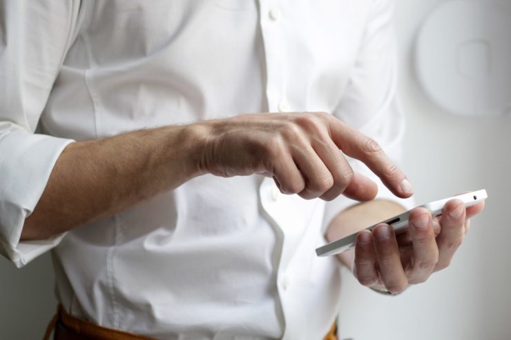 Torso of a man typing on a phone