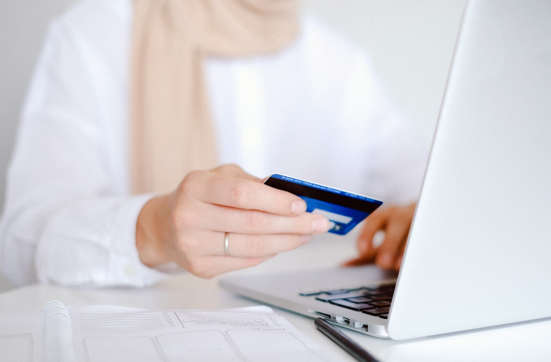 A woman holding a credit card while typing on a laptop.