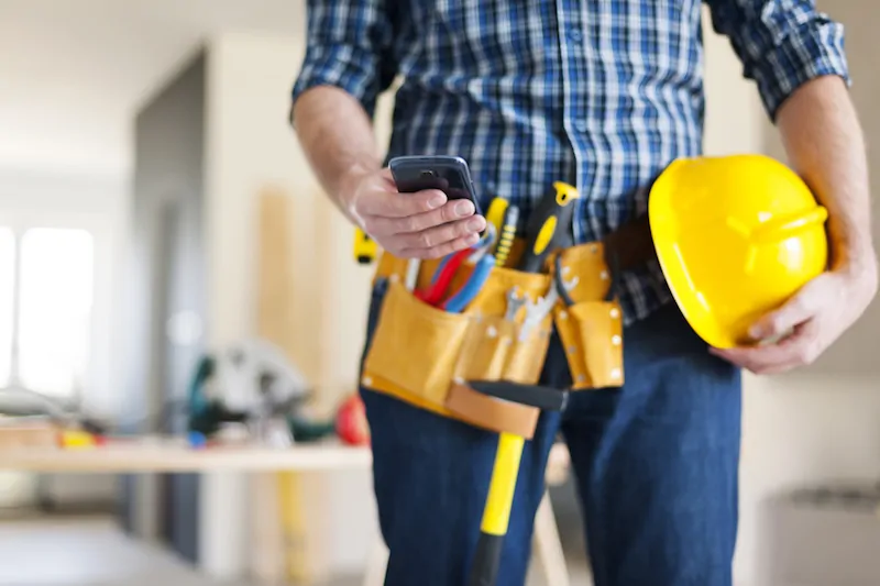 Close-up of construction worker holding cell phone