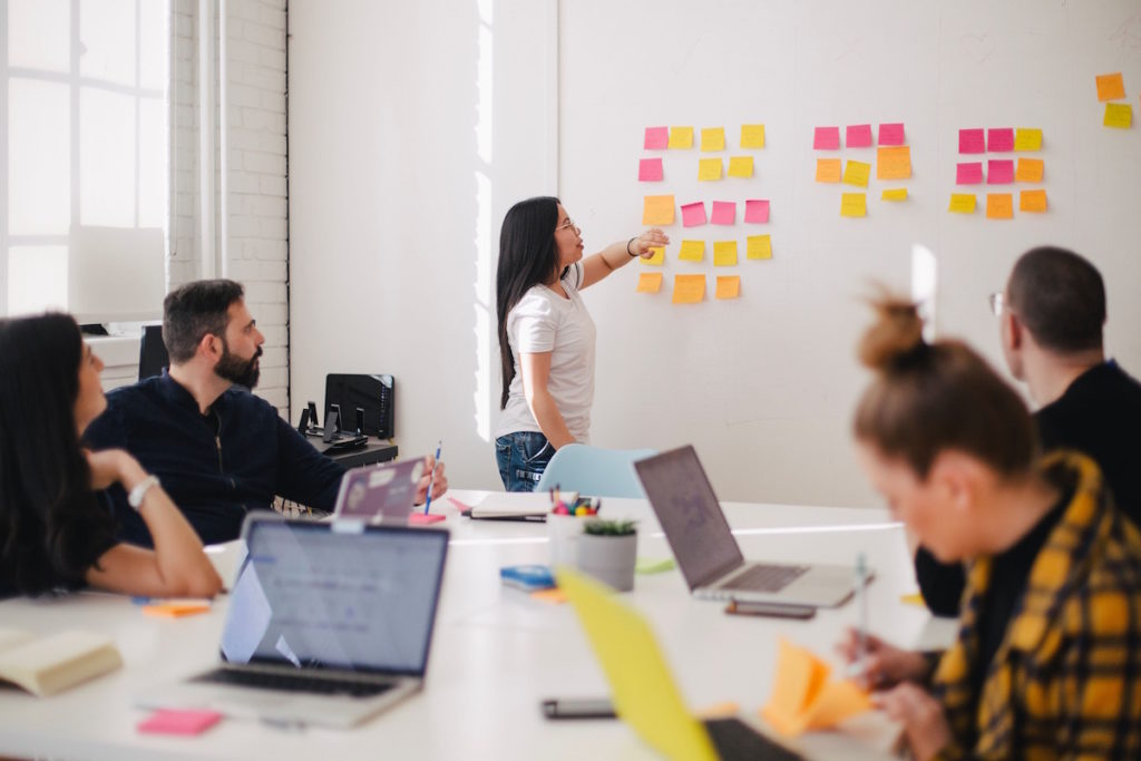 Woman placing sticky notes on a wall during a business meeting