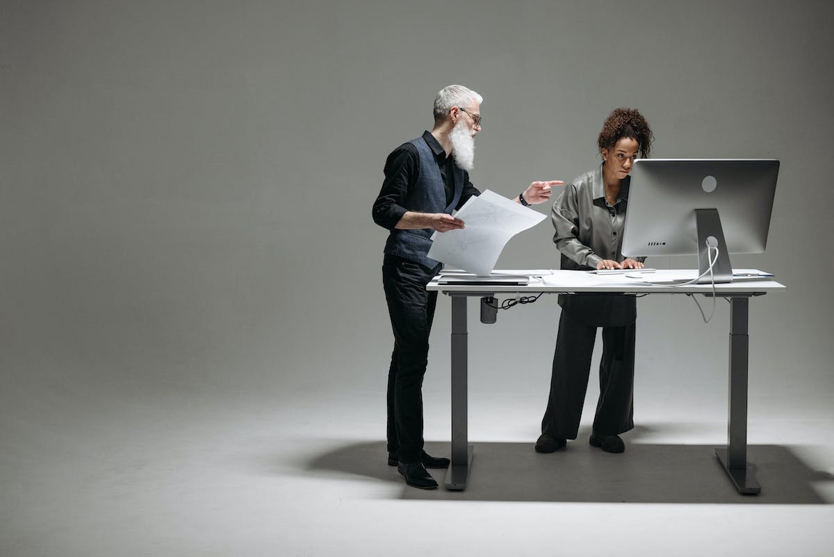 Two people working at a computer in an empty space.