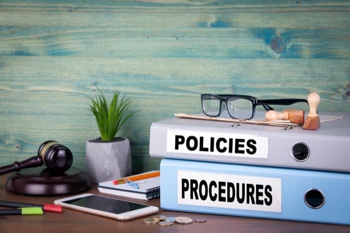 Policies and procedures binders stacked on desk