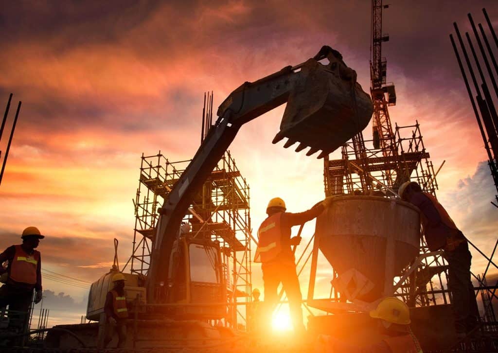 Silhouette of a worker and a crane against a sunset.