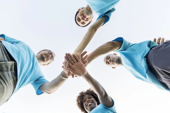 Group of happy and diverse volunteers stacking their hands on top of each other