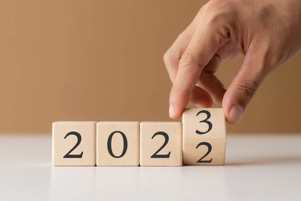 A hand turning a block of numbers with '2023' printed on them