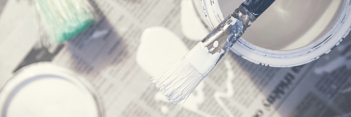 White paint buckets and a thin paint brush with white paint on it.