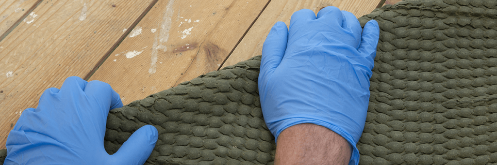 Hands in latex glover rolling up carpet