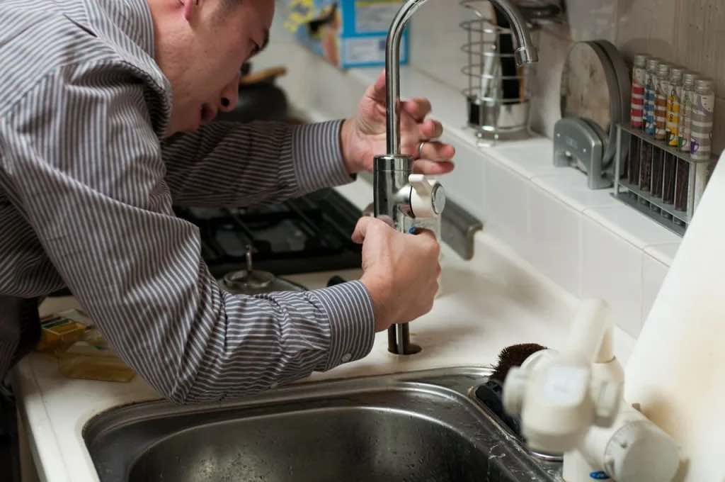 Plumber fixing a sink faucet