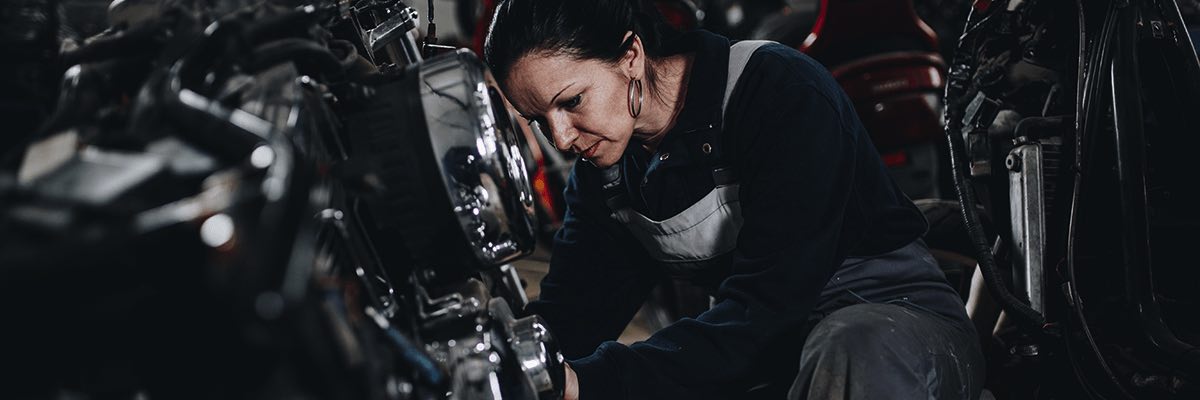 Strong and worthy woman doing hard job in car and motorcycle repair shop