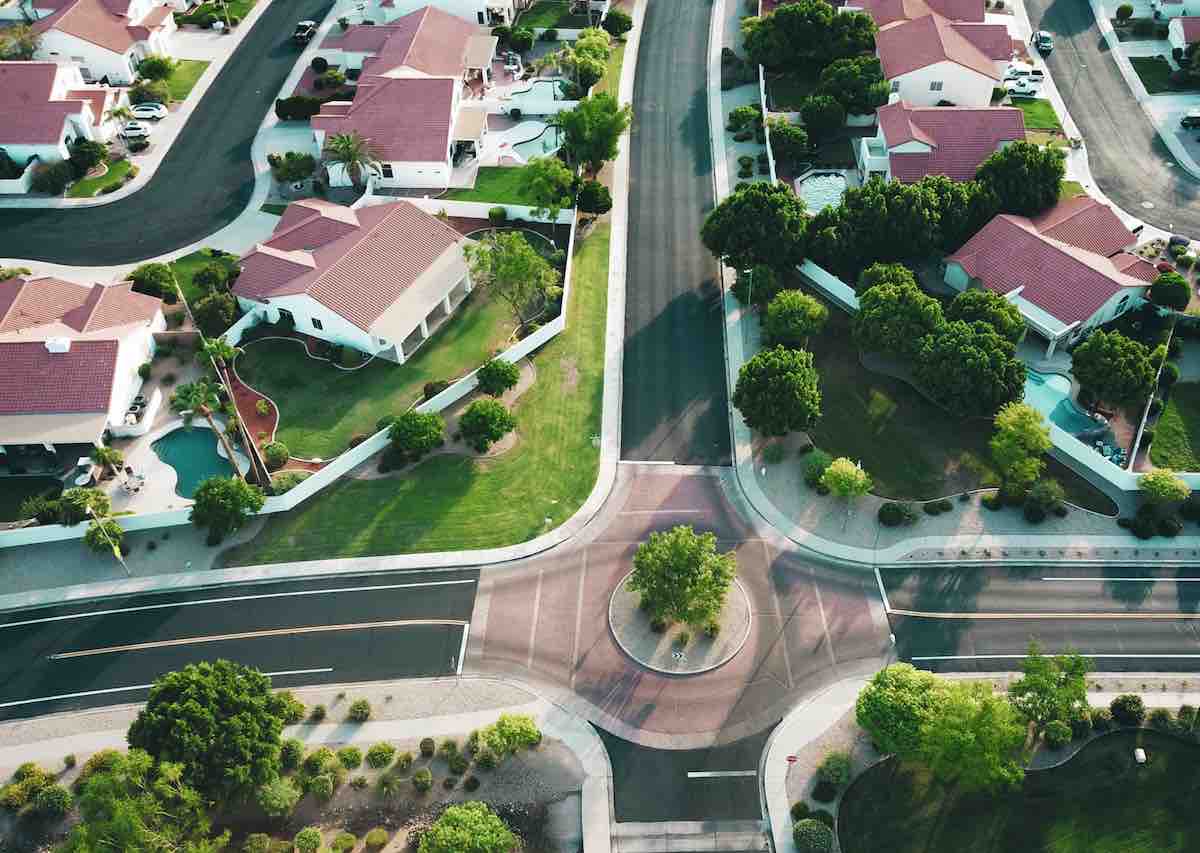 Drone shot looking forward in a suburb of white-and-red houses