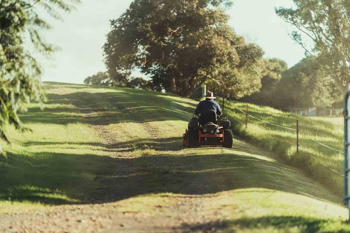 man riding on red atv on green grass field during daytime