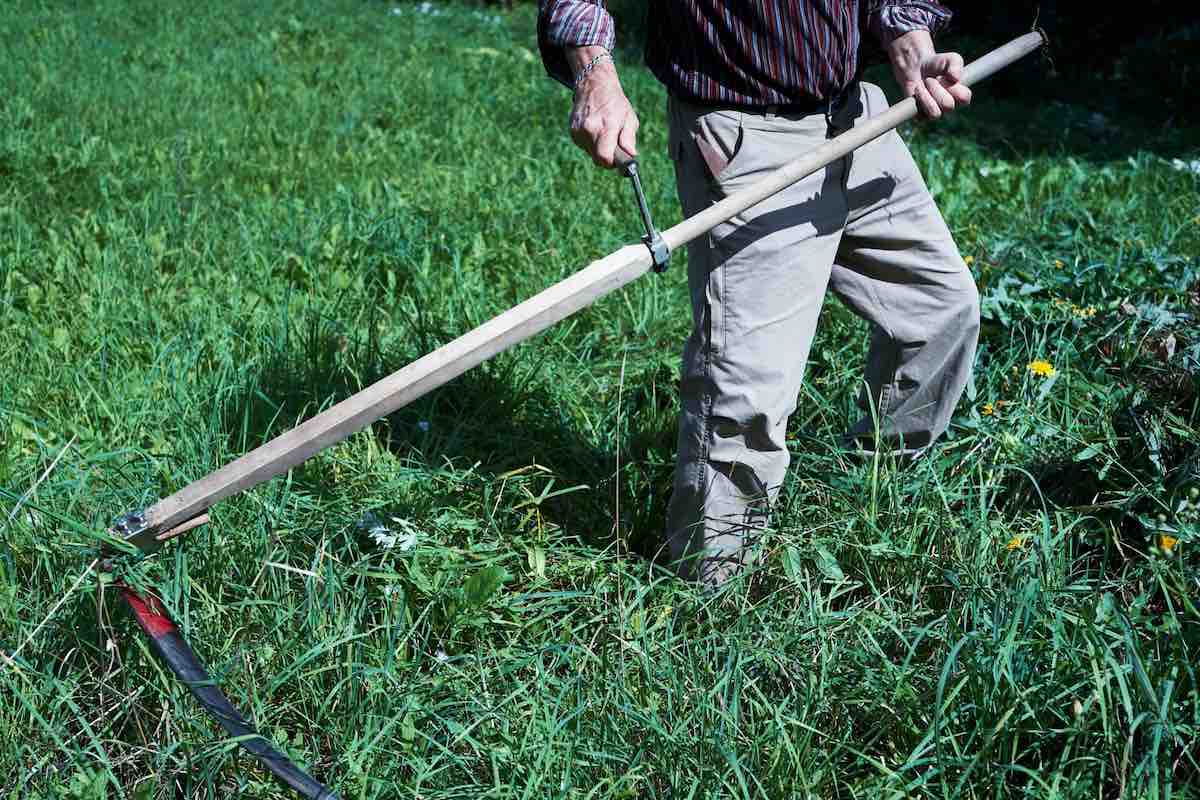 man in black and gray stripe long sleeve shirt and gray pants holding scythe