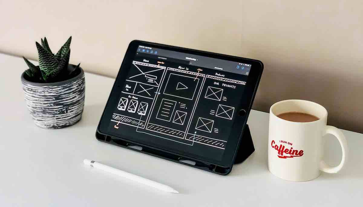 black ipad beside white ceramic mug on white table