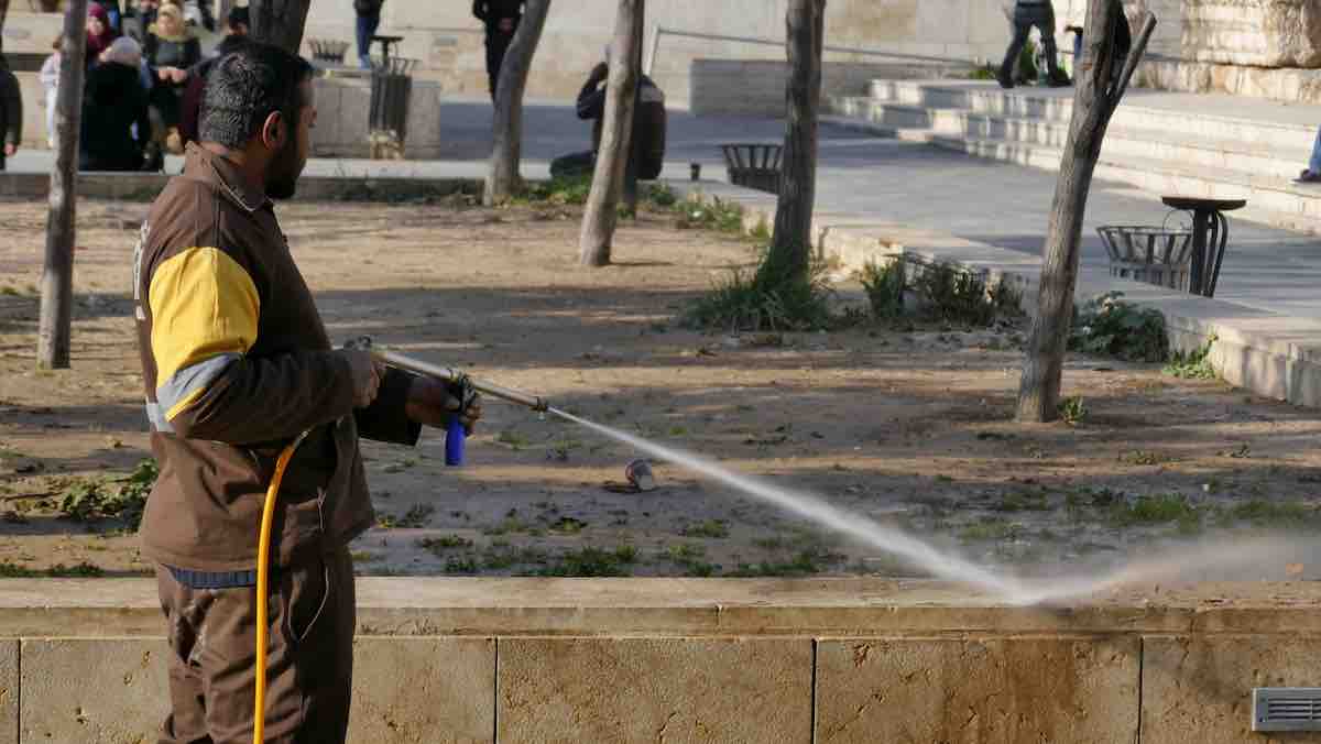 man in brown jacket cleaning concrete