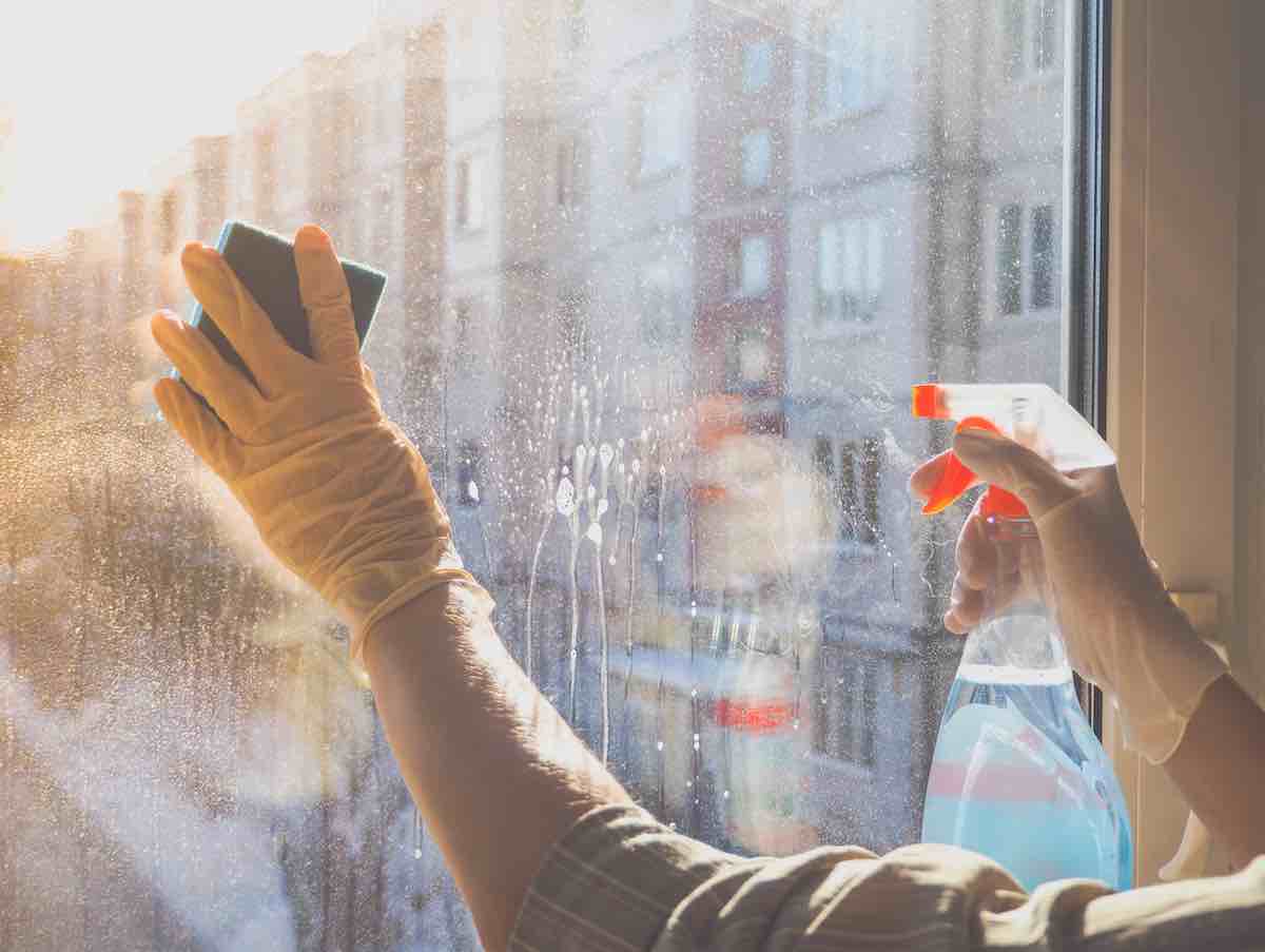 Hands in latex gloves cleaning a window