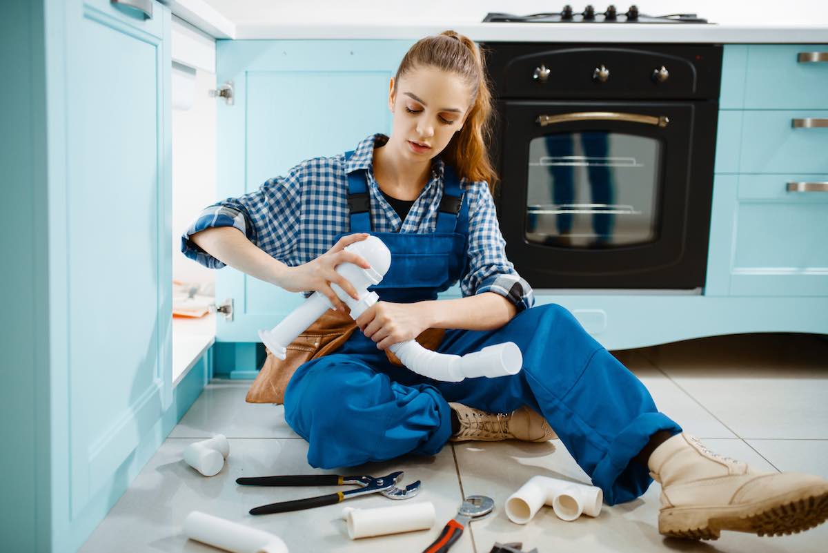 Female plumber fixing a drain pipe