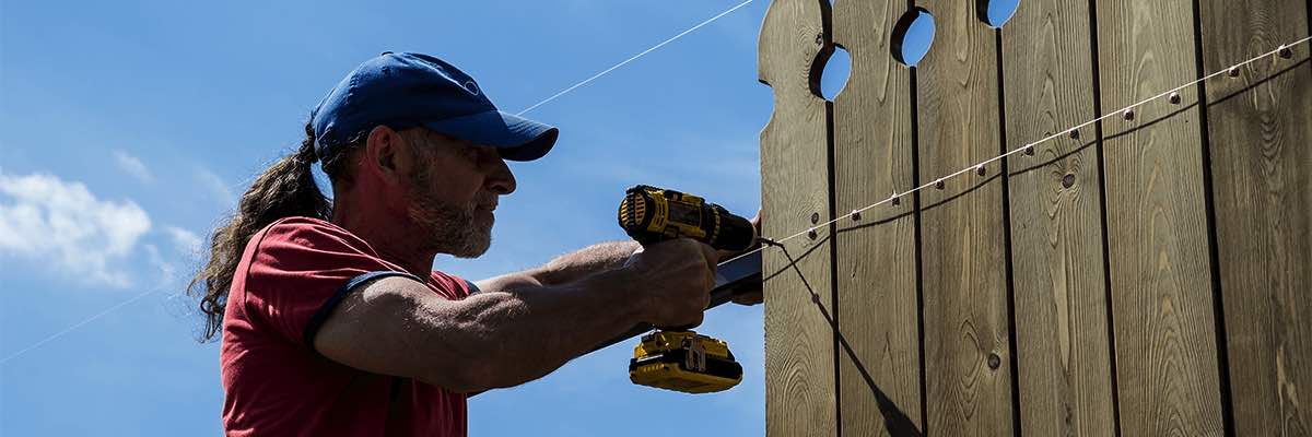 A man builds a wooden fence