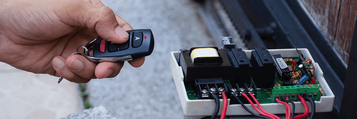 Technician man hand using remote control, testing and checking the functional of motor gear of sliding automatic gate.