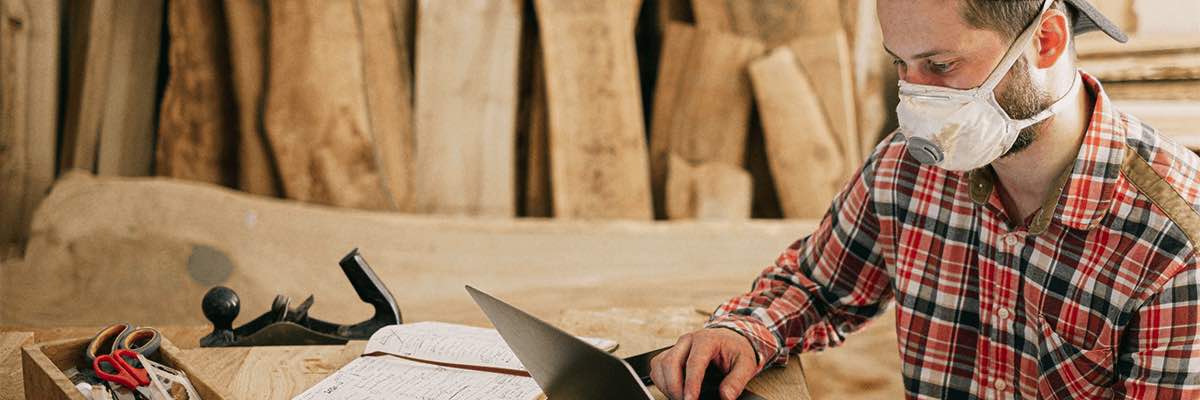 Man Using a Laptop at a Wood Workshop