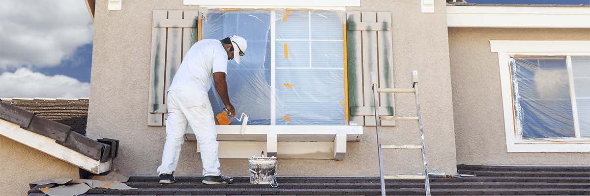 House Painter Painting the Trim And Shutters of Home