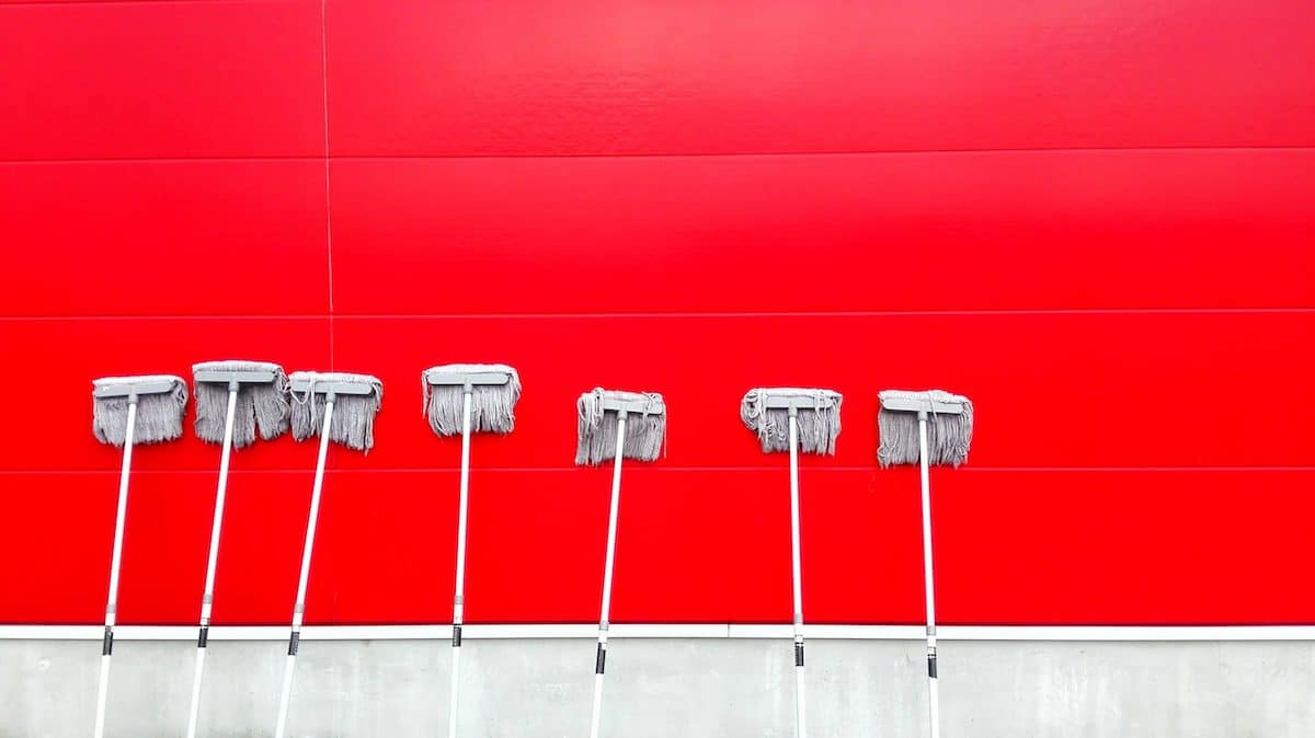 A red wall with 7 mops leaning against it