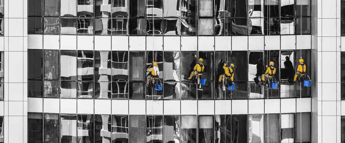 Five window cleaners in yellow cleaning a the windows a skyscraper