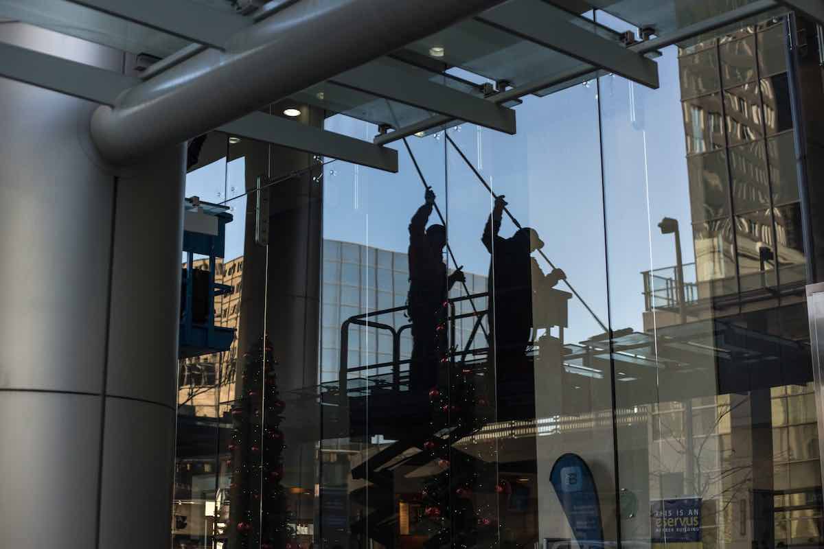 Reflection of two people on a window cleaning said window