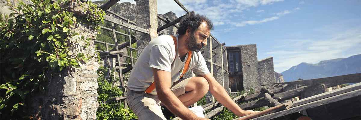 ocused man building roof of wooden construction