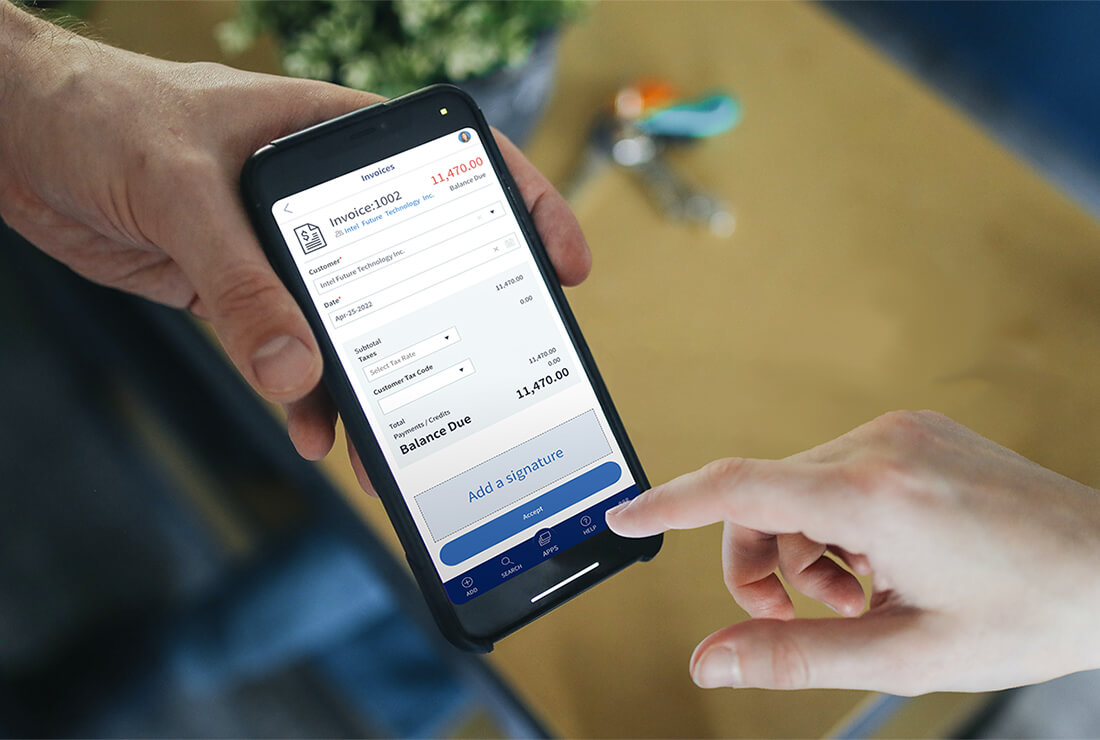 This image shows a person holding out a phone for someone else to digitally sign an invoice that is shown on the phone screen.