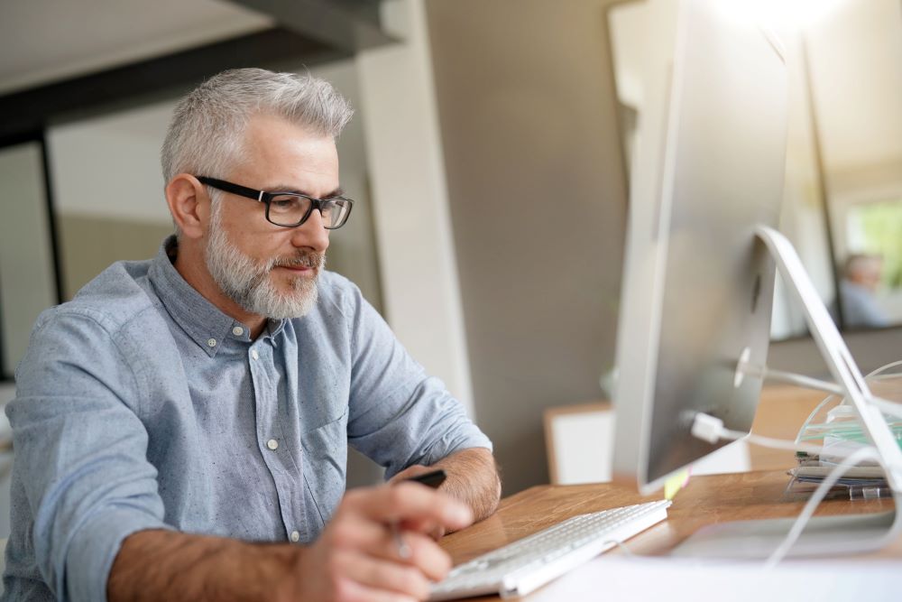 senior male working on a Mac desktop