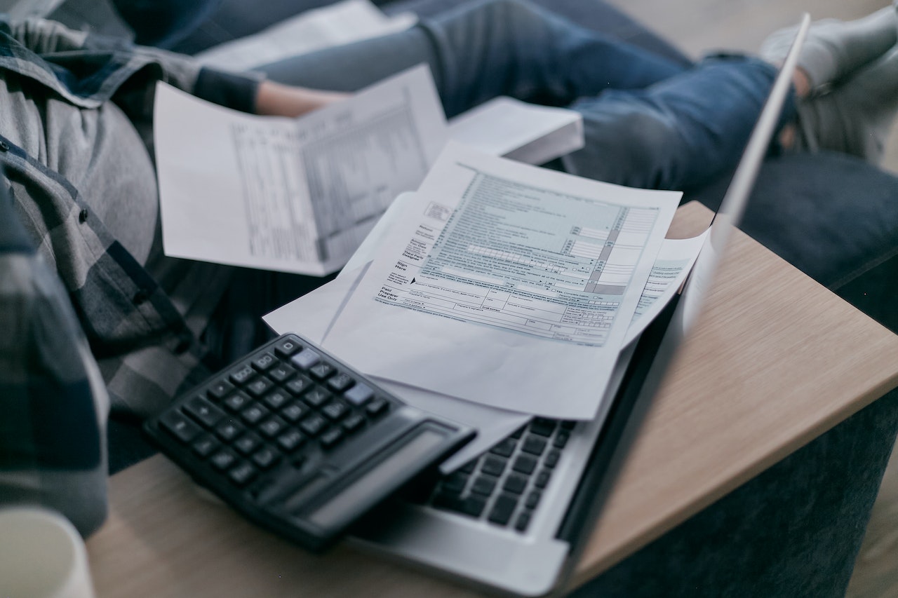 This image shows white papers and a calculator stacked atop a laptop computer.