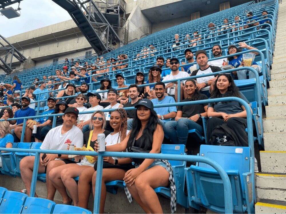 Method team members sitting at a football stadium with blue chairs and smiling at the camera.