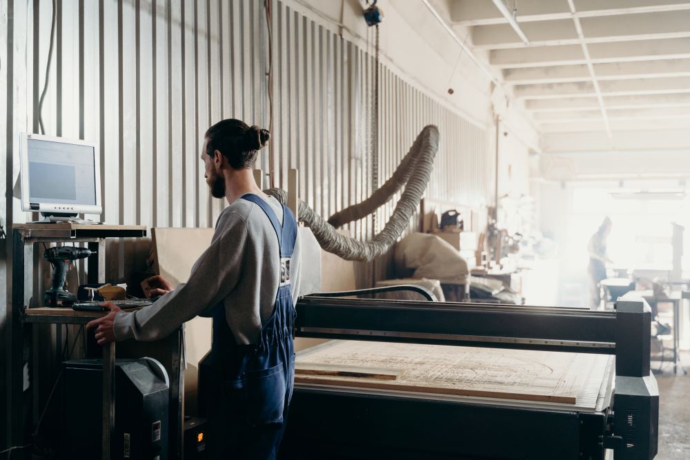 a man standing in front of a computer in a manufacturing plant