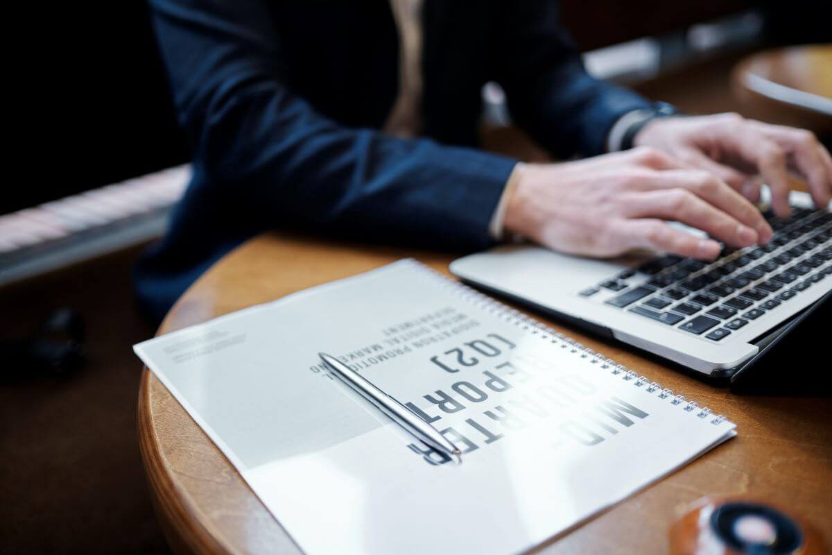 Man on a computer at a desk with a graph next to him.