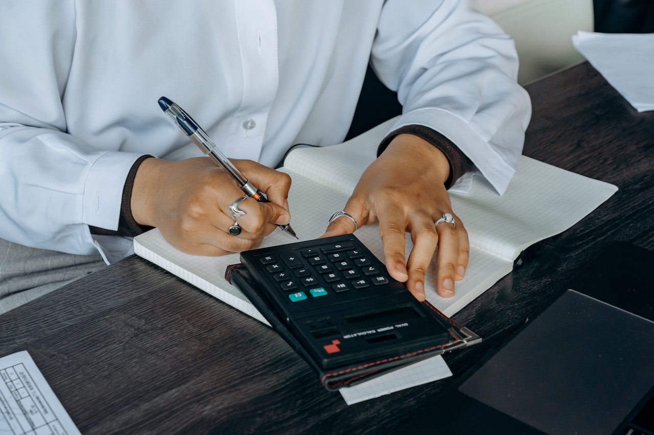 This image shows a person jotting down notes while using a calculator.