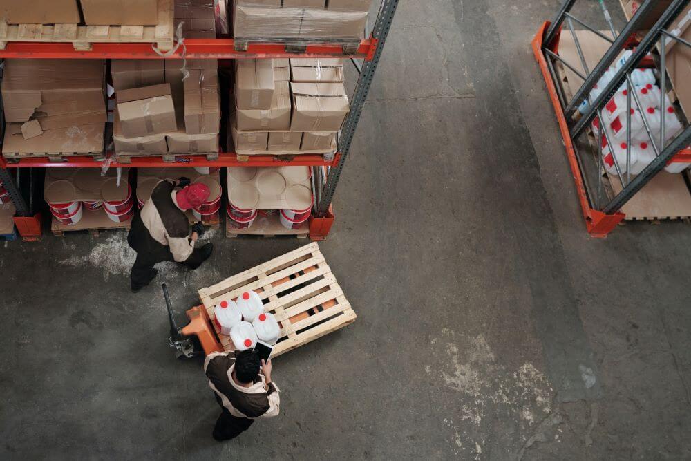 warehouse workers with some crates shown in a warehouse from a birds eye view