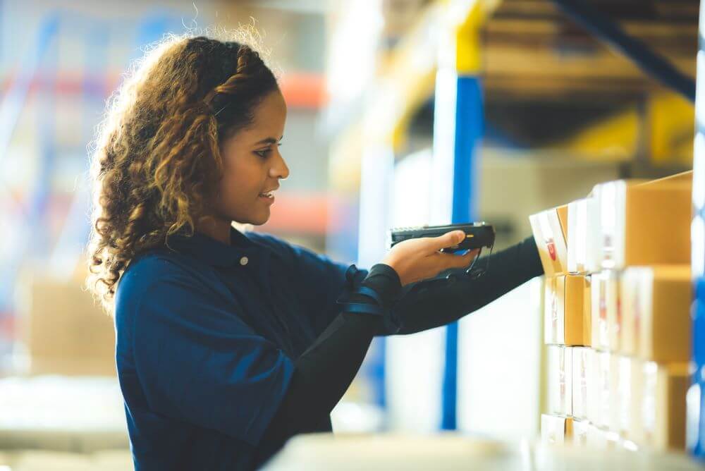 woman using a barcode a barcode scanner in a warehouse for products on a shelf