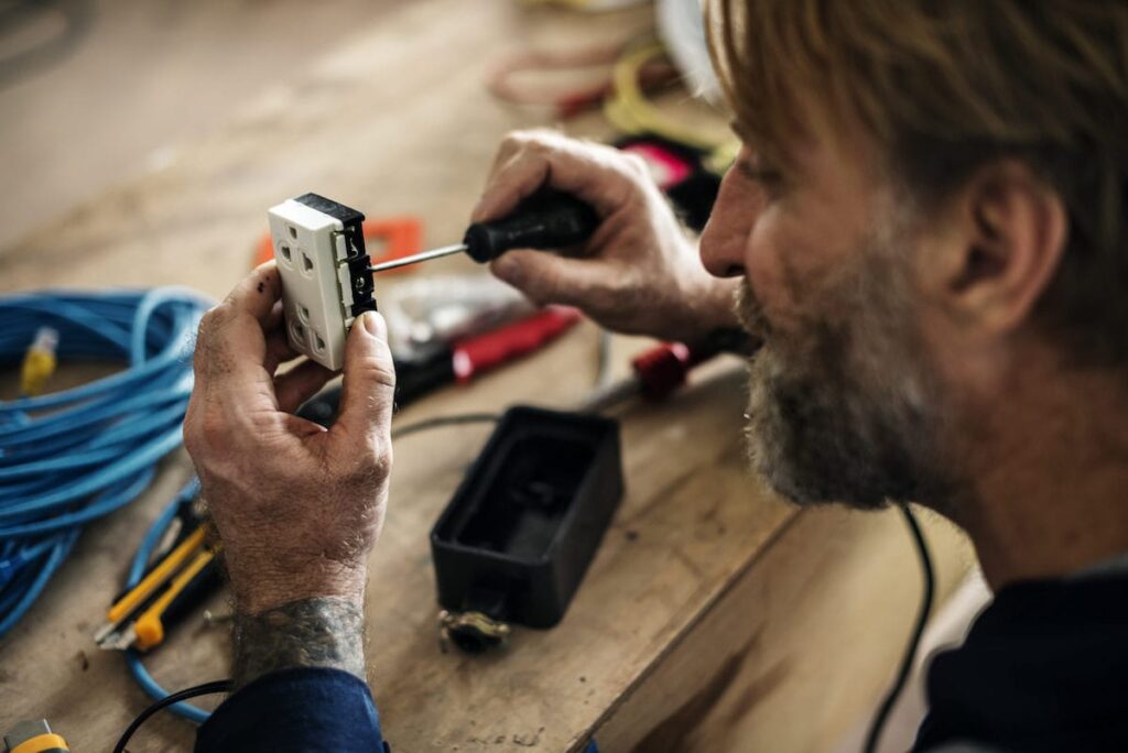 Close-up of man fixing an electrical outlet.