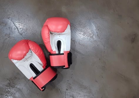 A pair of red and white boxing gloves lying on a wooden floor.