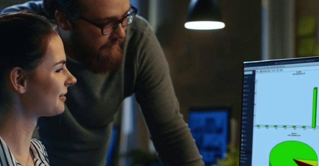 Two people at a computer looking at a QuickBooks Desktop screen