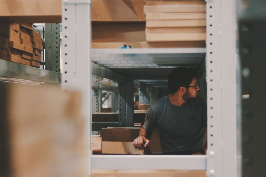 A man standing under large shelves in a warehouse.