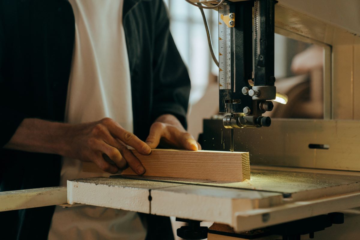 A man cutting a piece of wood with a tablesaw.