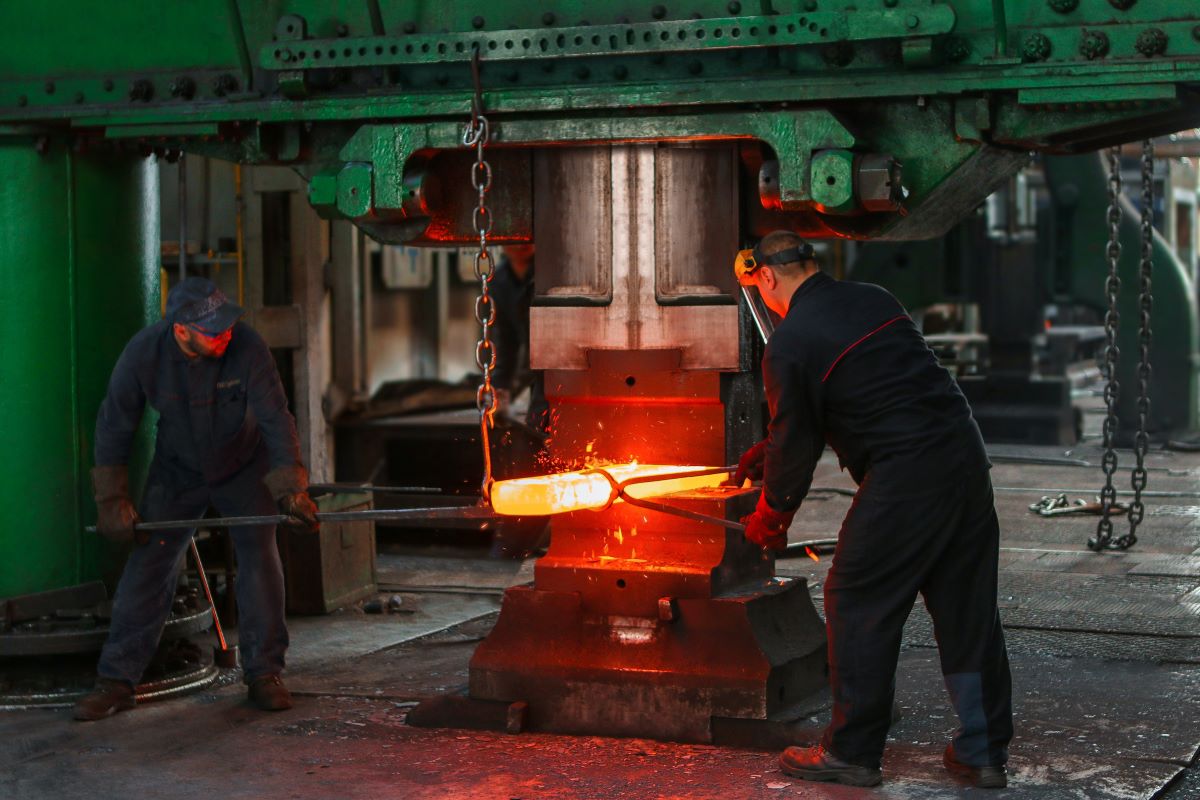 Two men forging a large piece of metal.