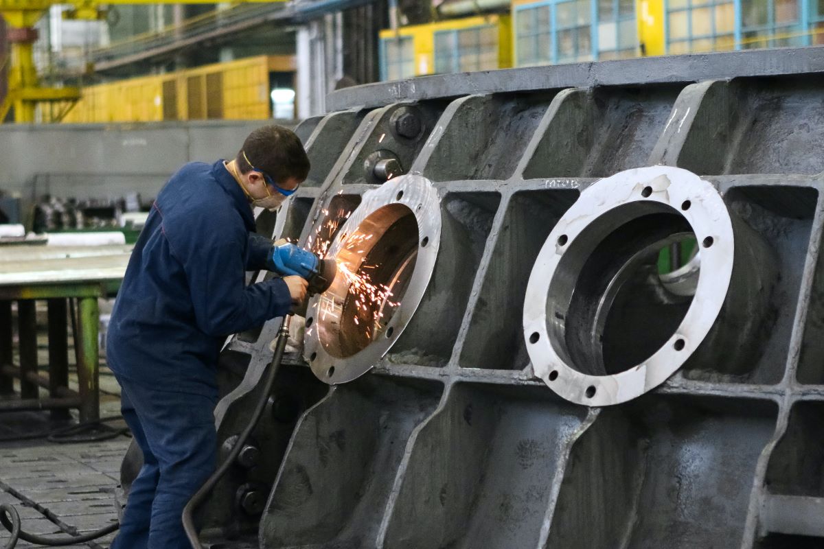 Man welding a round metal window frame.