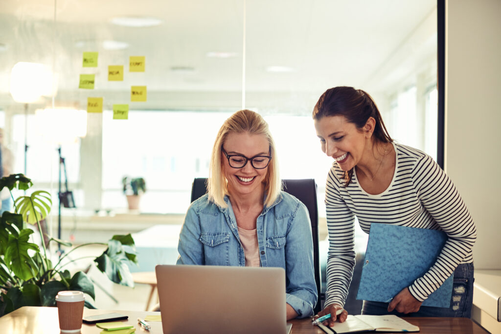 Smiling young businesswomen using a laptop together in an office.