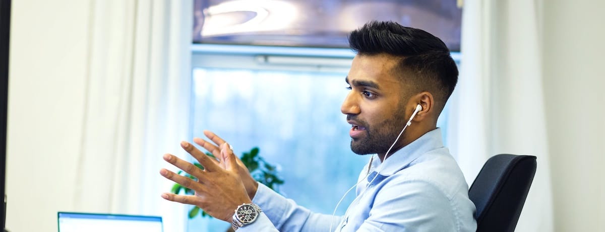 Man with earbuds talking in an office