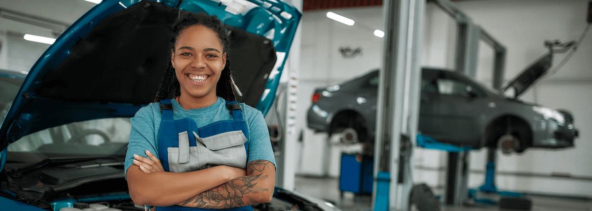 Smiling woman with arms crossed in an auto repair shop