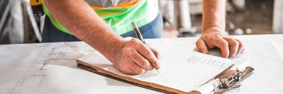 Close-up of a hand filling out a clipboard