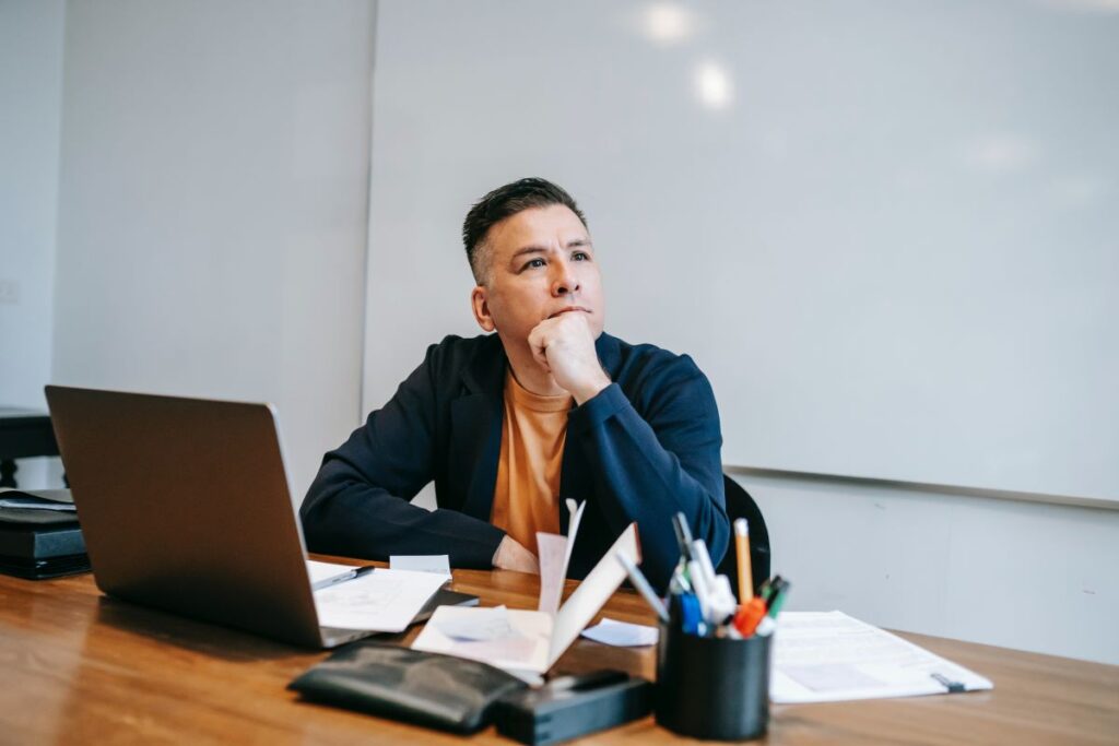 A man at his desk thinking with his hand on his chin.